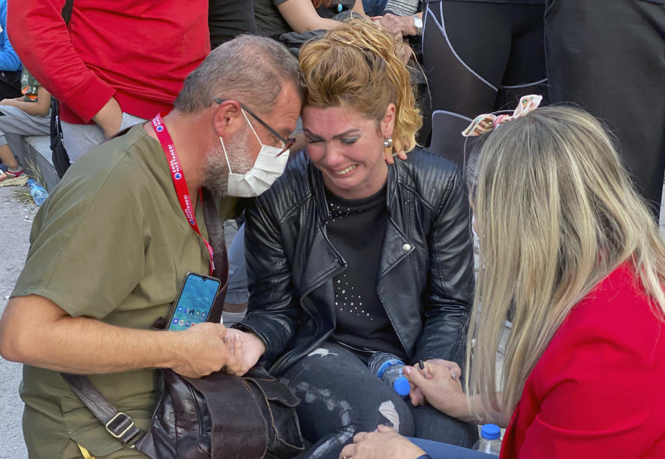 A woman weeps as rescue workers try to save people trapped in the debris of a collapsed building, in Izmir, Turkey, Friday, Oct. 30, 2020. A strong earthquake struck Friday in the Aegean Sea between the Turkish coast and the Greek island of Samos, killing several people and injuring hundreds amid collapsed buildings and flooding, officials said.(AP Photo/Ismail Gokmen)