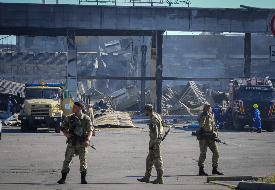 Ukrainian soldiers stand in front of a shopping center burned after a rocket attack in Kremenchuk, Ukraine, Tuesday, June 28, 2022. (AP Photo/Efrem Lukatsky)