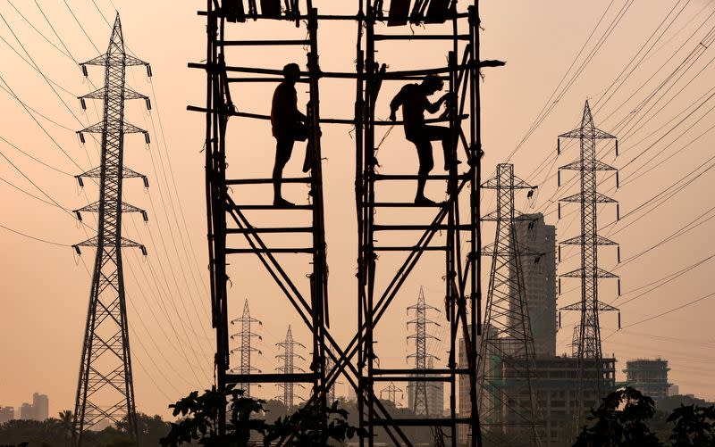 FILE PHOTO: Labourers work next to electricity pylons in Mumbai