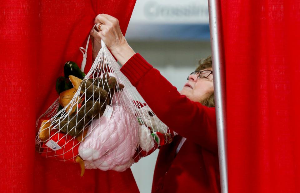 Volunteer Kathy Hoppes takes down a bundle of stuffed animals for a Share Your Christmas recipient at Crosslines on Thursday, Dec. 19, 2019.