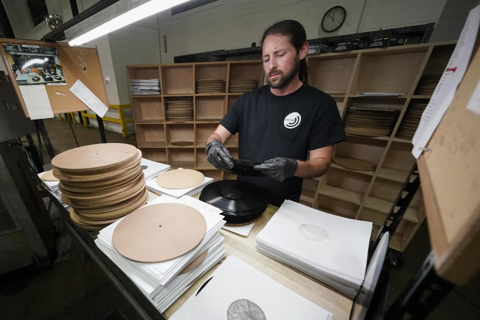 Ricky Riehl inspecciona discos de vinilo terminados en busca de defectos antes de que sean empaquetados, en las instalaciones de United Record Pressing, el jueves 23 de junio de 2022 en Nashville, Tennessee. (Foto AP/Mark Humphrey)