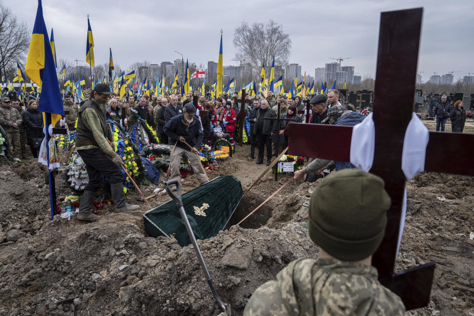 Funeral workers lower the coffin of Ukrainian serviceman Andrii Neshodovskiy during the funeral ceremony at the cemetery in Kyiv, Ukraine, Saturday, March 25, 2023. (AP Photo/Evgeniy Maloletka)