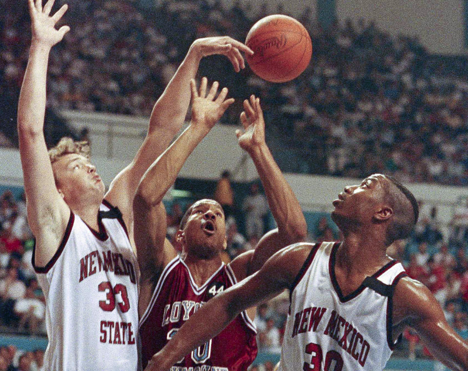FILE - Loyola Marymount's Bo Kimble, center, and New Mexico State's Jason Trask, left, and James Anderson, battle for the ball during an NCAA college basketball tournament first round game in Long Beach, Calif., March 16,1990. Loyola Marymount suffered an unspeakable tragedy in the 1990 West Coast Conference tournament when burly forward Hank Gathers collapsed on the court and later died of heart condition. Playing while grieving, Bo Kimble scored 45 points against New Mexico State in the opening round of the NCAA Tournament and led the Lions to the Elite Eight as a No. 11 seed.(AP Photo/Doug Sheridan, File)