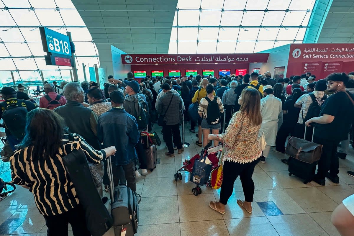 Passengers queue at a flight connection desk at the Dubai International Airport in Dubai (AFP via Getty Images)