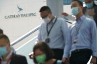 People wearing face masks following the coronavirus disease (COVID-19) outbreak, walk out of Cathay City, the headquarters of Cathay Pacific