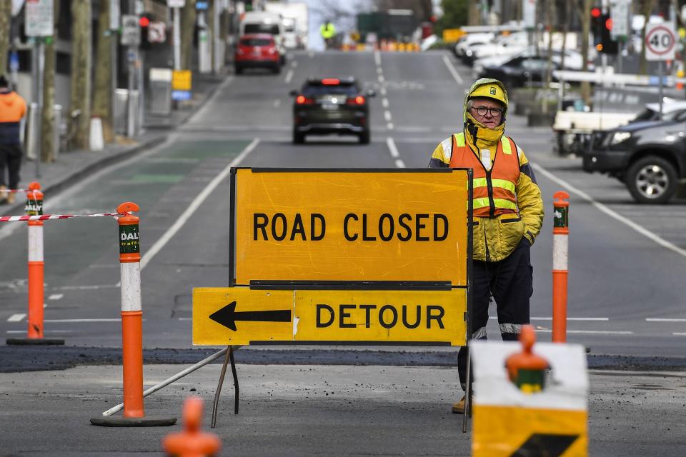 A worker stands besides a road sign in Melbourne on July 21, 2020. - Australia will extend record stimulus spending into next year, the government announced on July 21, outlining multi-billion-dollar measures to shield the labour market from the ravages of the rolling coronavirus crisis. (Photo by William WEST / AFP) (Photo by WILLIAM WEST/AFP via Getty Images)