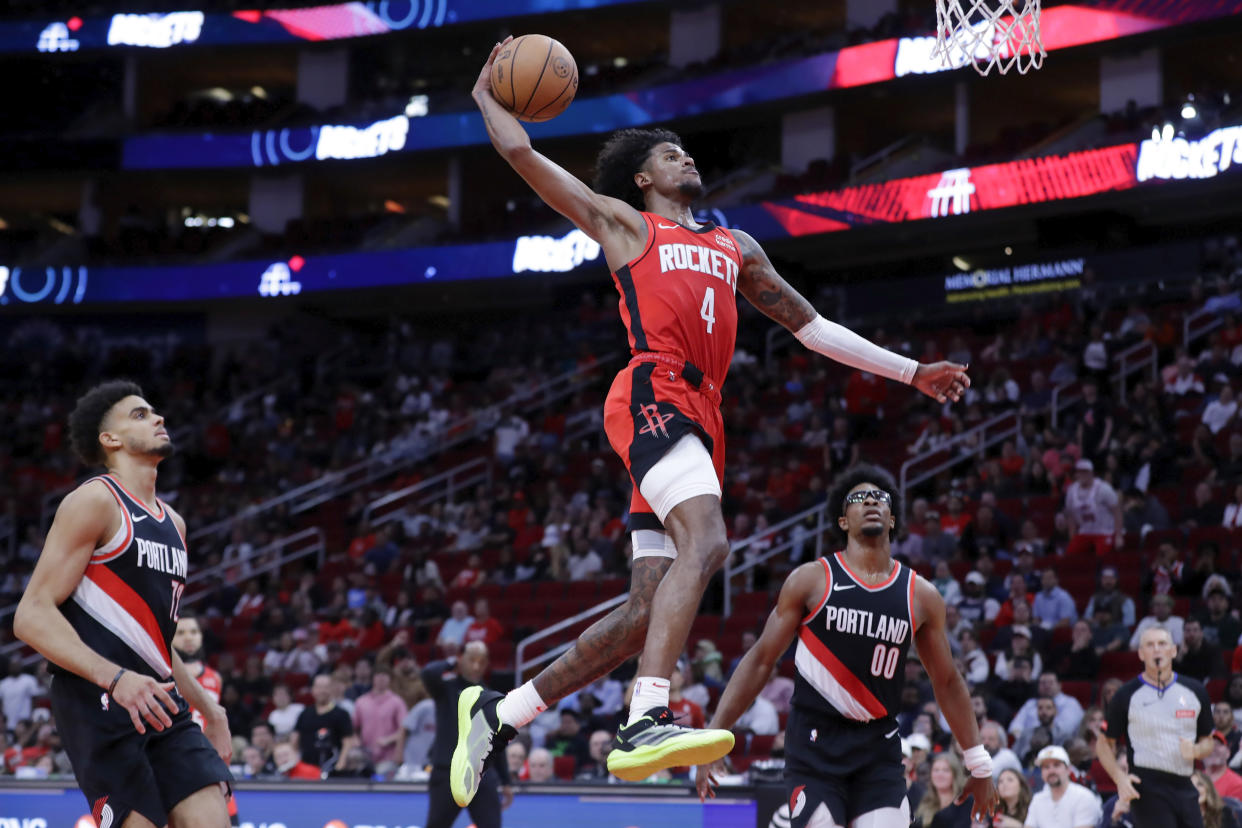 Houston Rockets guard Jalen Green (4) dunks the ball between Portland Trail Blazers guards Rayan Rupert, left, and Scoot Henderson (00) during the second half of an NBA basketball game Monday, March 25, 2024, in Houston. (AP Photo/Michael Wyke)