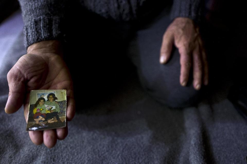 In this Thursday, Jan. 19, 2017 photo, Ibraheem Ghareeb, 55, a Syrian refugee from al-Zohour Street in Aleppo, shows a photograph of his daughters, Mariam, when she was 7-year-old and currently 20 and lives in Germany, and his late daughter Layla, 13, who passed away in 2004 back in Syria, at his tent in Kalochori refugee camp on the outskirts of the northern Greek city of Thessaloniki. " This is the only physical memory that I have left of my late daughter Layla and it never leave my sight." Ibraheem said. (AP Photo/Muhammed Muheisen)