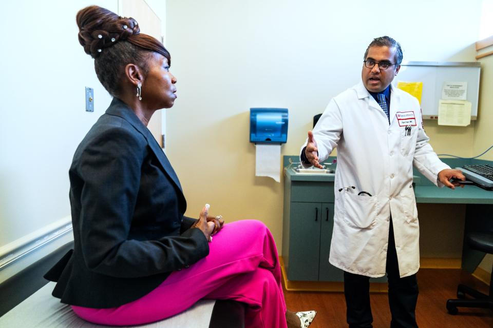 Keenya Taylor, left, speaks with Dr. Ajaykumar Rao during a routine appointment. Doctors say too much paperwork interferes with their ability to work with patients.