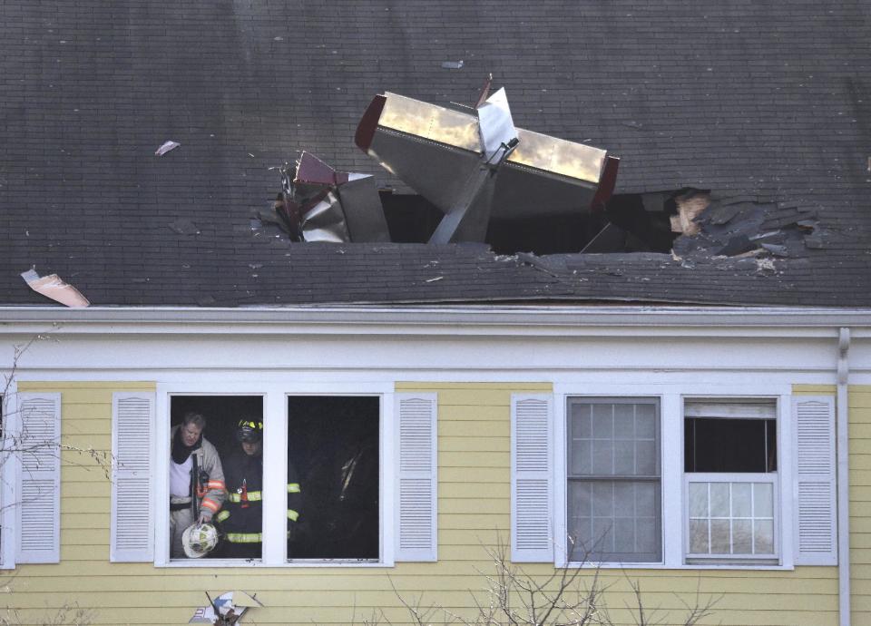 Firefighters investigate the scene after a small plane crashed into the roof of a condominium building across the Merrimack River from Lawrence Municipal Airport, Tuesday, Feb. 28, 2017, in Methuen, Mass. (AP Photo/Elise Amendola)