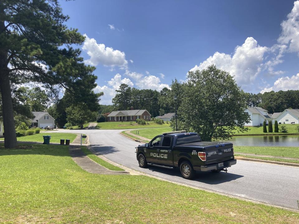 A police vehicle stands guard in the Dogwood Lakes neighborhood in Hampton, Ga., on Sunday, July 16, 2023. Police say a man who lived in the brick house in the background shot and killed four people in the neighborhood on Saturday, July 15. (AP Photo/Jeff Amy)