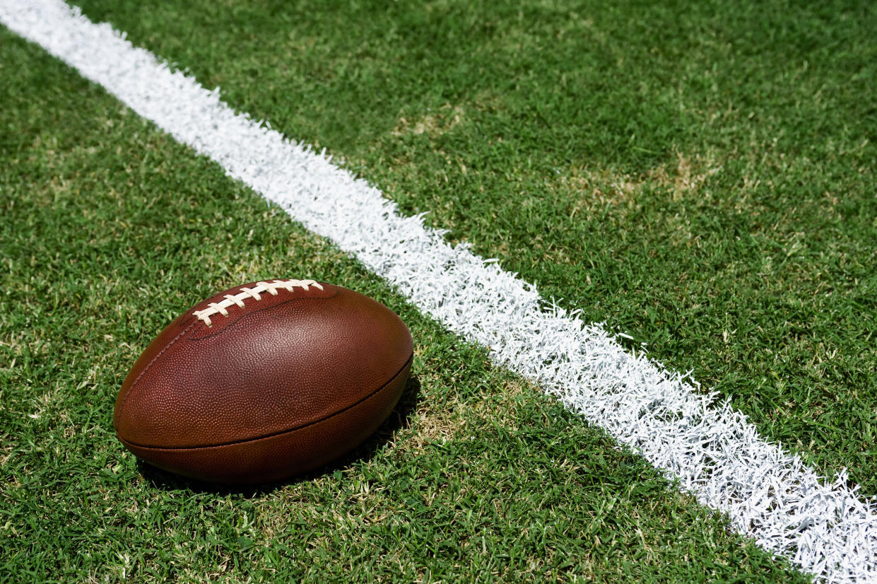 Football sitting on the grass next to a yard line