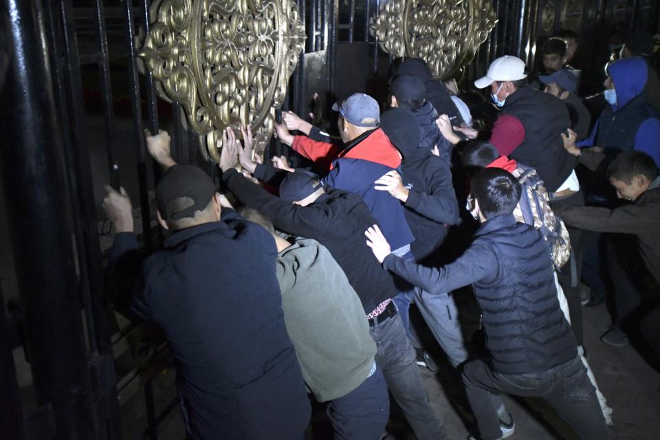People try to storm the gate into the government headquarters during a rally against the results of a parliamentary vote in Bishkek, Kyrgyzstan, Monday, Oct. 5, 2020. Large crowds of people have gathered in the center of Kyrgyzstan's capital to protest against the results of a parliamentary election, early results of which gave the majority of seats to two parties with ties to the ruling elites amid allegations of vote buying. (AP Photo/Vladimir Voronin)