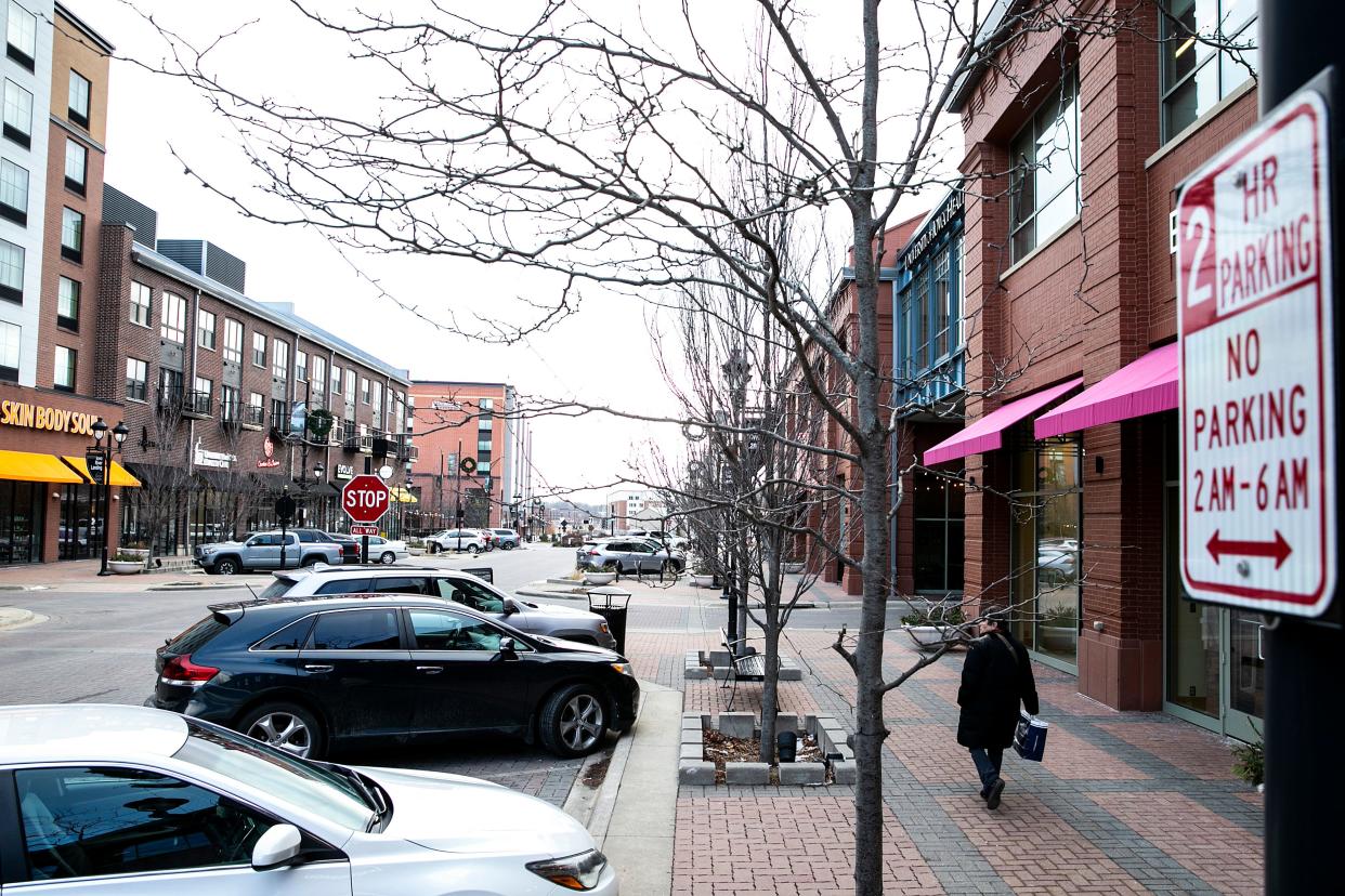 A person walks along 2nd Avenue past parked cars, Friday, Jan. 20, 2023, at the Iowa River Landing in Coralville, Iowa.