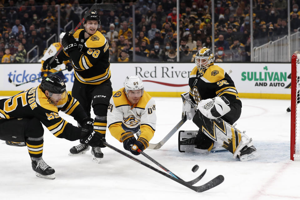 Nashville Predators' Mikael Granlund dives for a loose puck in front of Boston Bruins goaltender Linus Ullmark with defenseman Tyler Lewington, left, during the second period of an NHL hockey game Saturday, Jan. 15, 2022, in Boston. (AP Photo/Winslow Townson)