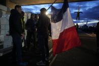Farmers gather under a bridge where hangs a dummy farmer as they block a highway Tuesday, Jan. 30, 2024 in Jossigny, east of Paris. With protesting farmers camped out at barricades around Paris, France's government hoped to calm their anger with more concessions Tuesday to their complaints that growing and rearing food has become too difficult and not sufficiently lucrative. (AP Photo/Christophe Ena)