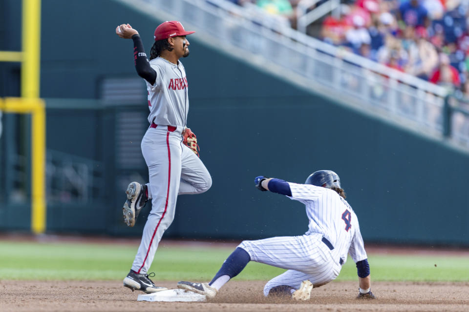 Arkansas shortstop Jalen Battles (2) turns a double play against Auburn's Brody Moore (4) in the first inning during an NCAA College World Series baseball game Tuesday, June 21, 2022, in Omaha, Neb. (AP Photo/John Peterson)