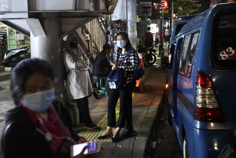 People wearing mask as a precaution against coronavirus outbreak, wait for public transport in Jakarta, Indonesia, Thursday, Dec. 3, 2020. (AP Photo/Dita Alangkara)