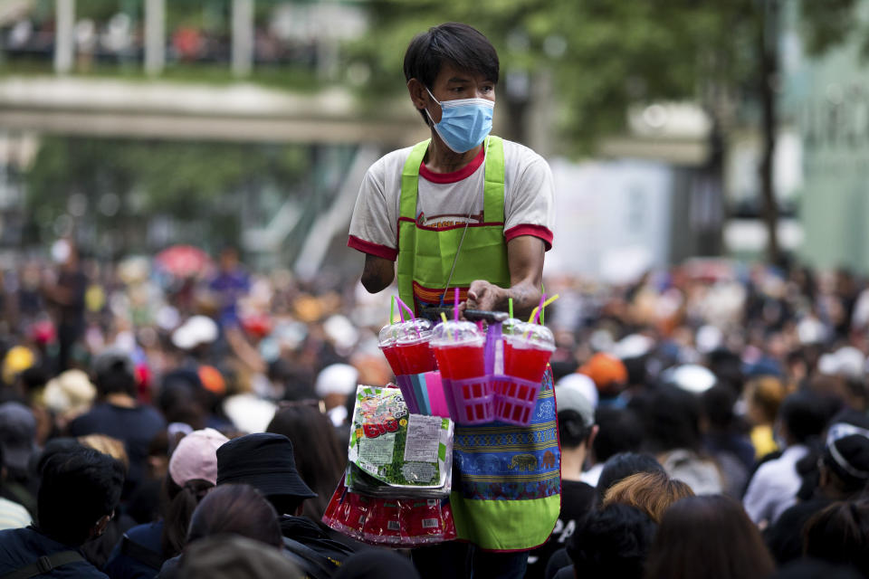 A vendor sells drinks at an anti-government rally at a major intersection in Bangkok, Thailand, Wednesday, Nov. 18, 2020. Police in Thailand's capital braced for possible trouble Wednesday, a day after a protest outside Parliament by pro-democracy demonstrators was marred by violence that left dozens of people injured. (AP Photo/Wason Wanichakorn)