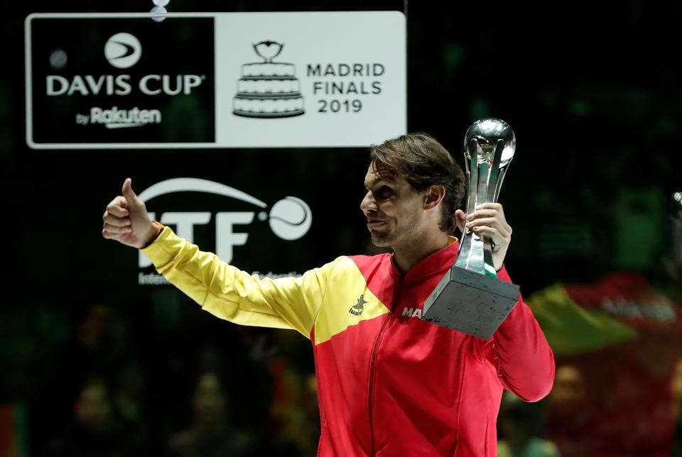 Rafa Nadal sonríe y saluda mientras sujeta un trofeo tras un partido.