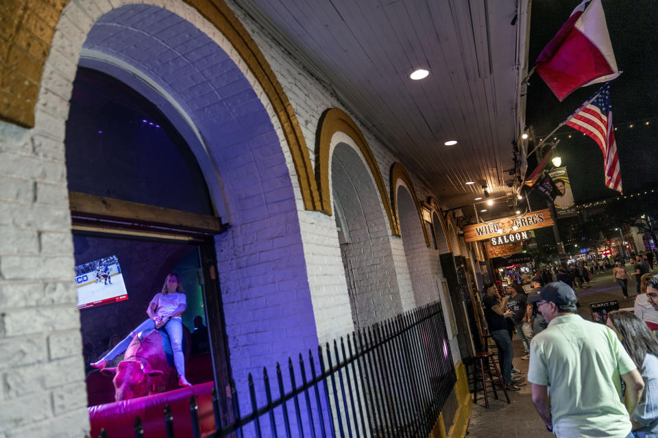 A patron rides a mechanical bull at a bar lining a popular nightlife district in Austin, Texas, Saturday, April 22, 2023. Since the early 1600s, ranchers raising cattle would cement the image of longhorn steers, rugged cowboys and awe-inspiring vistas into the nation's consciousness as what it means to be a Texan. The state has changed dramatically since then, but that image remains today and keeps beef in the forefront of life in Texas. (AP Photo/David Goldman)