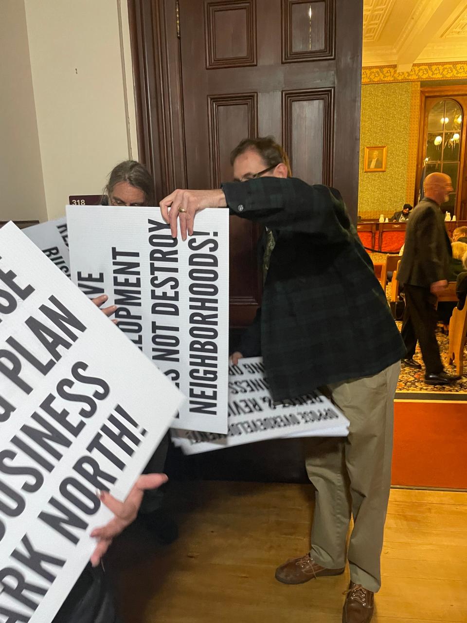 Norwich resident Frederick Browning (center) passes out signs at Tuesday night's city council meeting, where zoning needed for the controversial Business Park North was defeated.