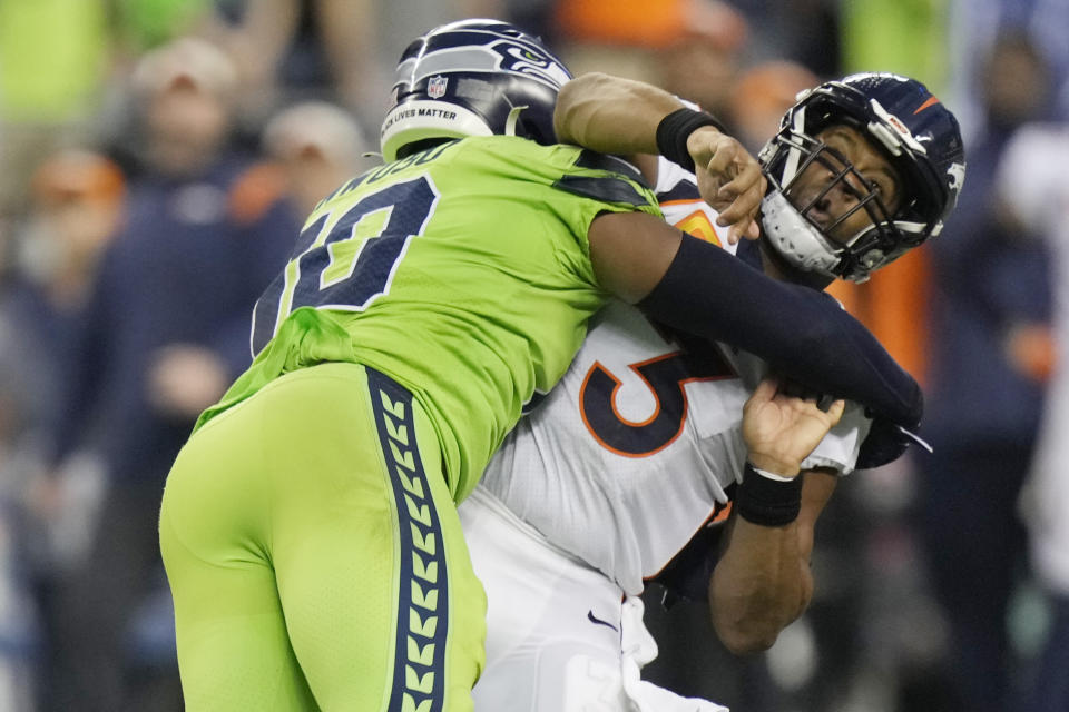 Denver Broncos quarterback Russell Wilson, right, is hit by Seattle Seahawks linebacker Uchenna Nwosu, left, after gettin a pass off during the second half of an NFL football game, Monday, Sept. 12, 2022, in Seattle. (AP Photo/Stephen Brashear)