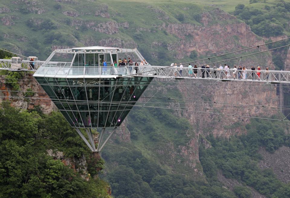 a glass bar suspended in the air in the middle of a glass bridge above Dashbashi Canyon in the country of Georgia