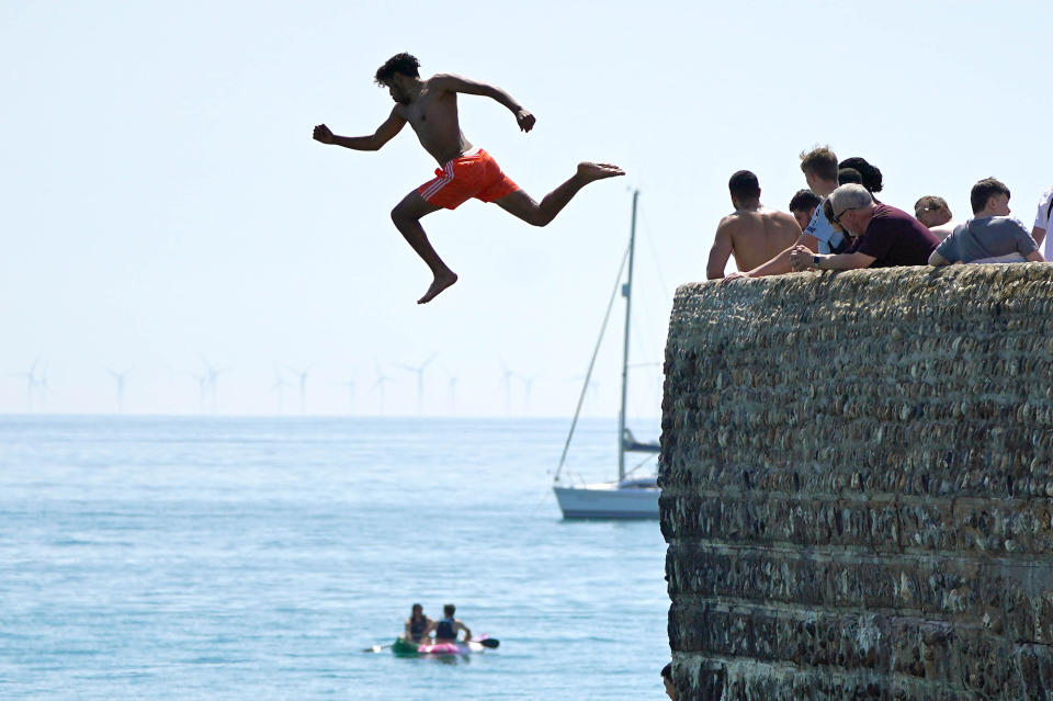 <p>A man jumps into the sea whilst people enjoy the sunshine on Brighton beach. Wednesday could be the hottest day of the year so far as parts of the UK are set to bask in 30-degree heat. Picture date: Wednesday June 16, 2021.</p>
