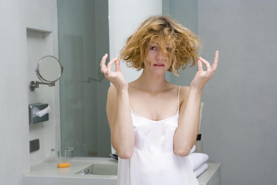 A worried-looking woman touches her hair