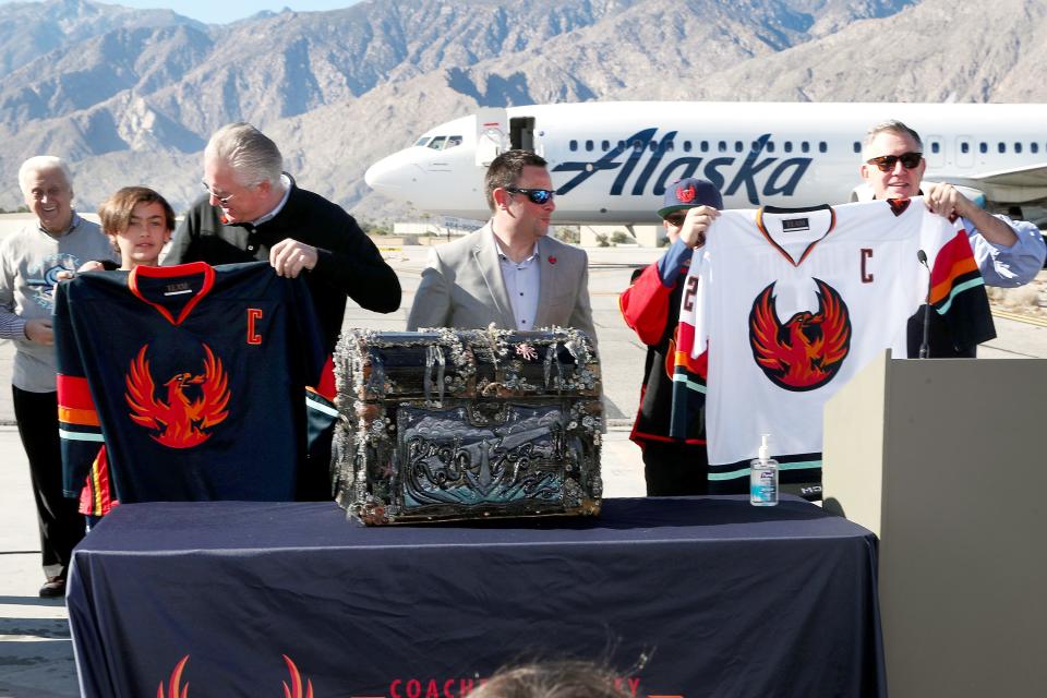 Jordan Veillieux, 12, left, and Tod Leiweke hold the home jersey for the Coachella Valley Firebirds hockey team as Seth Heinrich and Tim Leiweke hold the away jersey during an event at the Palm Springs Air Museum in Palm Springs, Calif., on Monday, Jan. 24, 2022. 