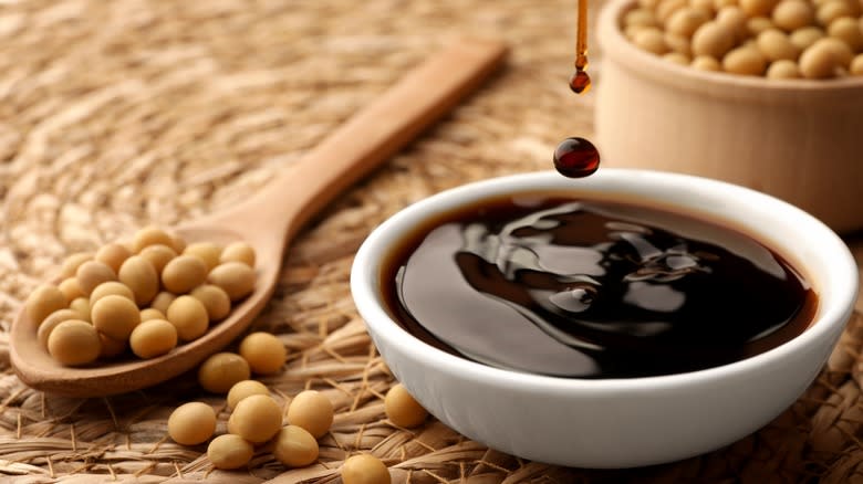 White dish of soy sauce next to soy beans 