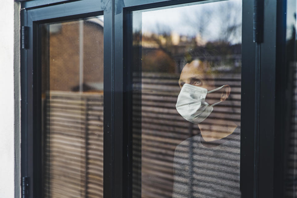 Man self-isolating at home looks out the window