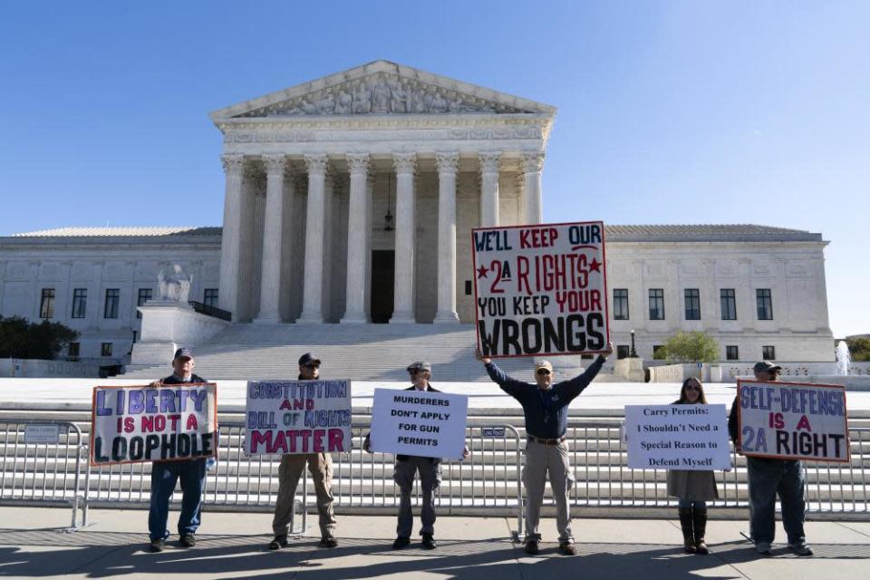 A group of six demonstrators hold signs outside the supreme court supporting gun rights.