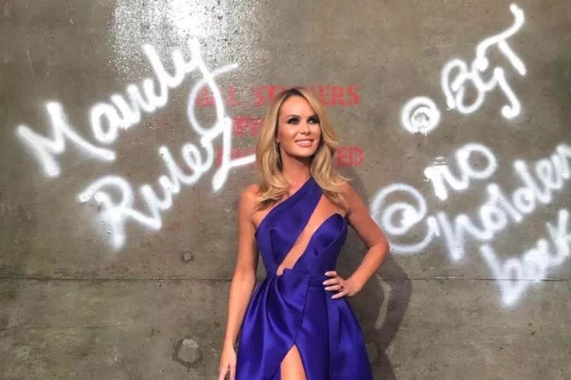 Standing against her famous 'Mandy Rulez' wall in the studio, she looked sensational in the deep blue dress