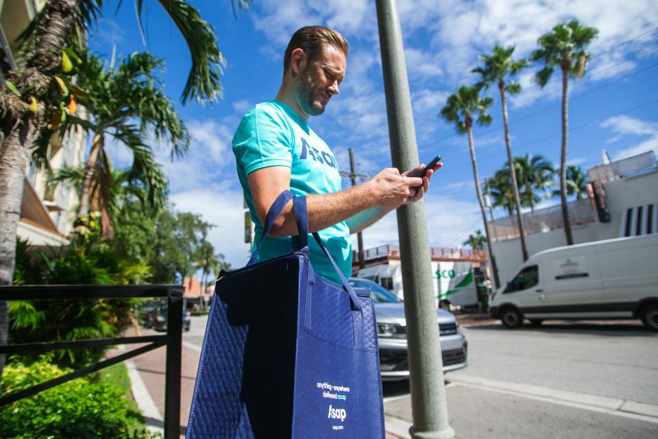 Christopher Lamu, a part-time driver for ASAP for three years, verifies a customer's address on the ASAP app after picking up a meal from Two Fat Breggfast on Monday, October 31, 2022, in downtown Delray Beach, FL. As of October 20, the delivery service originally known as Delivery Dudes became ASAP.