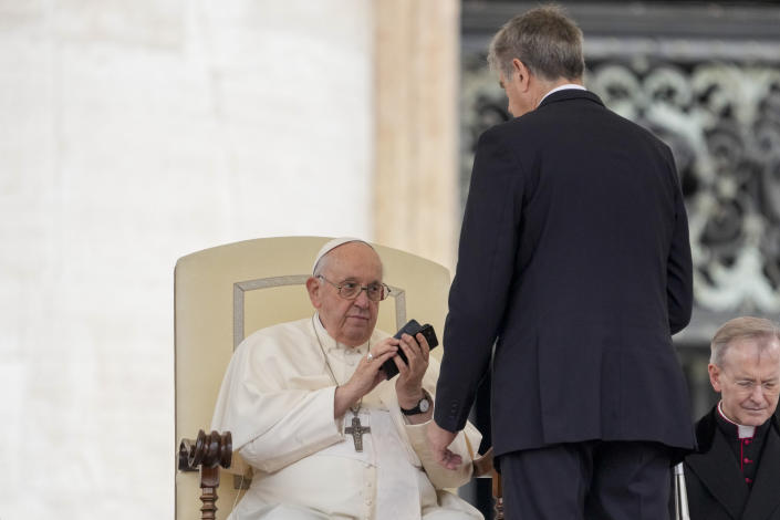 Pope Francis returns a cellphone at the end of a call he received during his weekly general audience in the St. Peter's Square at the Vatican, Wednesday, May 17, 2023. (AP Photo/Andrew Medichini)