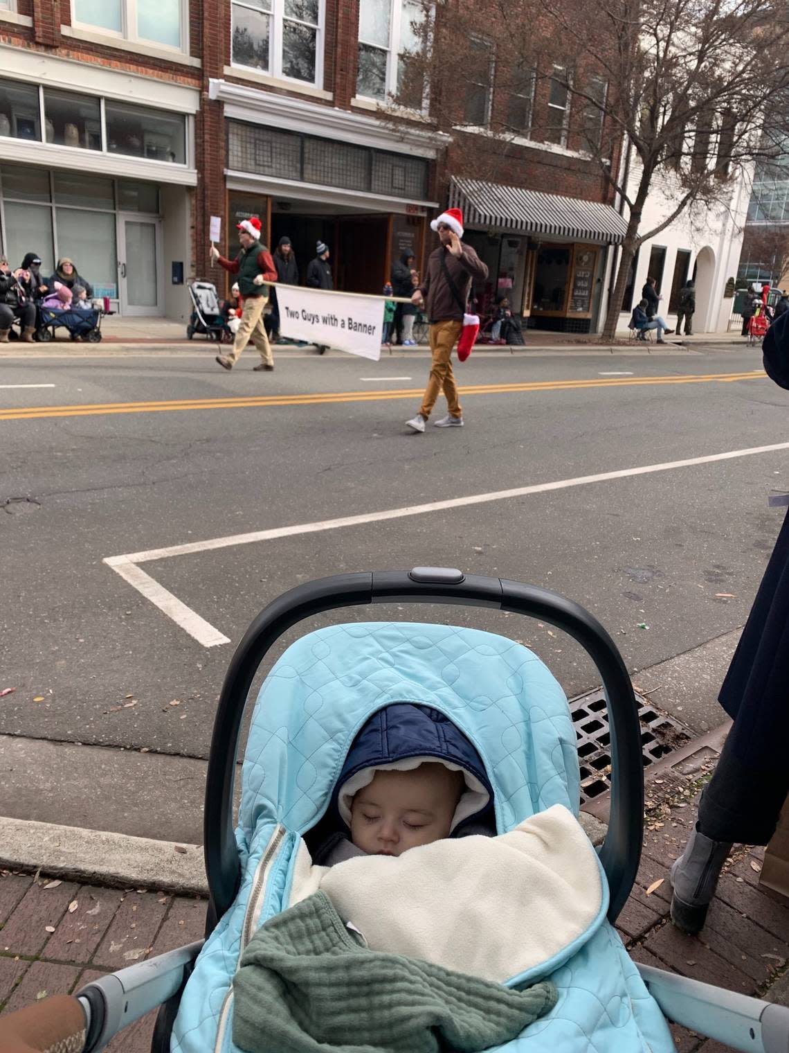 The reporter’s three-month-old taking in the Durham Holiday Parade and its popular float, “Two Guys With a Banner.”