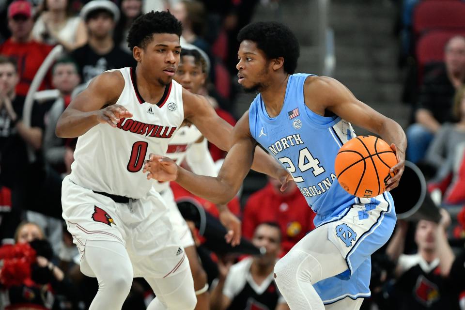 Feb 1, 2022; Louisville, Kentucky, USA;  North Carolina Tar Heels guard Kerwin Walton (24) dribbles against Louisville Cardinals guard Noah Locke (0) during the second half at KFC Yum! Center. North Carolina defeated Louisville 90-83.