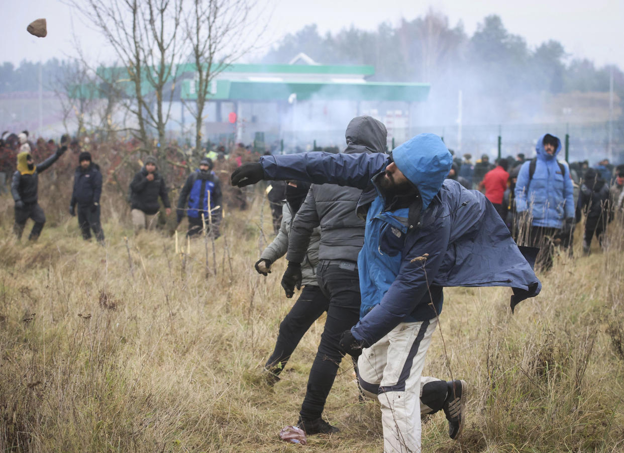 A man throws a stone during clashes with Polish border guards at the Belarus-Poland border near Grodno, Belarus, on Tuesday, Nov. 16, 2021. Polish border forces say they were attacked with stones by migrants at the border with Belarus and responded with a water cannon. The Border Guard agency posted video on Twitter showing the water cannon being directed across the border at a group of migrants in a makeshift camp. (Leonid Shcheglov/BelTA via AP)