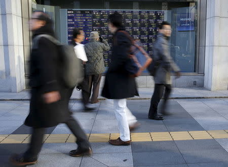 A man (3rd L) looks at an electronic stock quotation board as passers-by walk past, outside a brokerage in Tokyo, Japan January 20, 2016. REUTERS/Toru Hanai