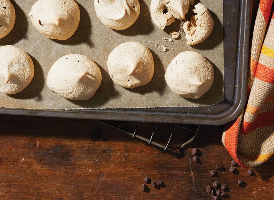 Chocolate coffee meringues on a baking tray with chocolate chips and a dish towel
