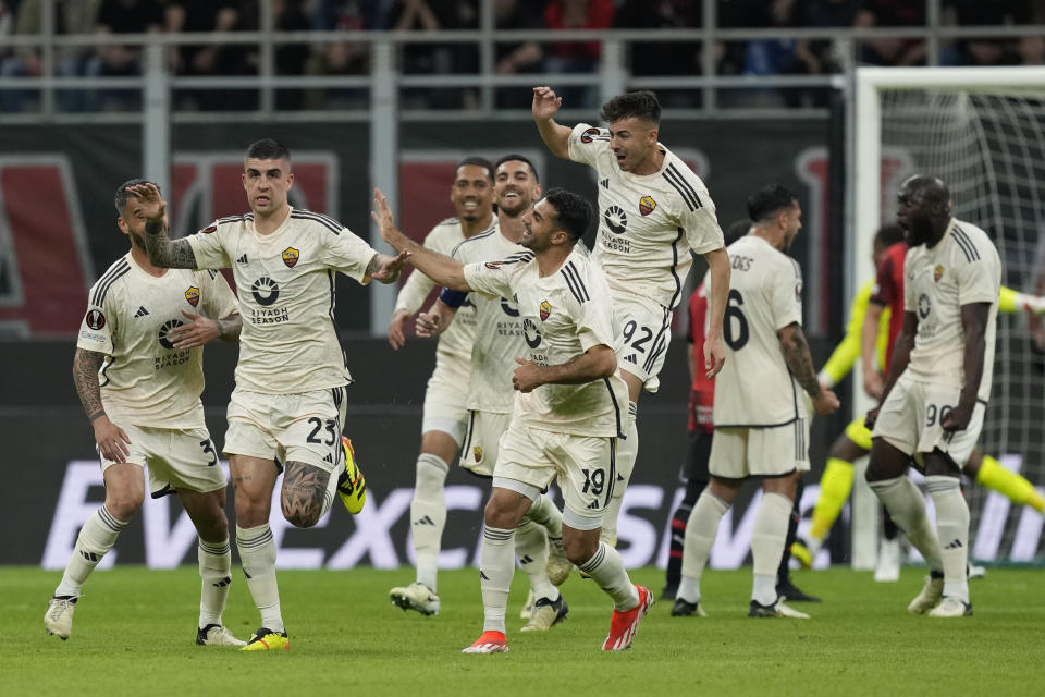 Roma's Gianluca Mancini, left, celebrates with his teammates after he scored his side's first goal during the Europa League quarterfinal first leg soccer match between AC Milan and Roma at the San Siro Stadium, in Milan, Italy, Thursday, April 11, 2024. (AP Photo/Antonio Calanni)