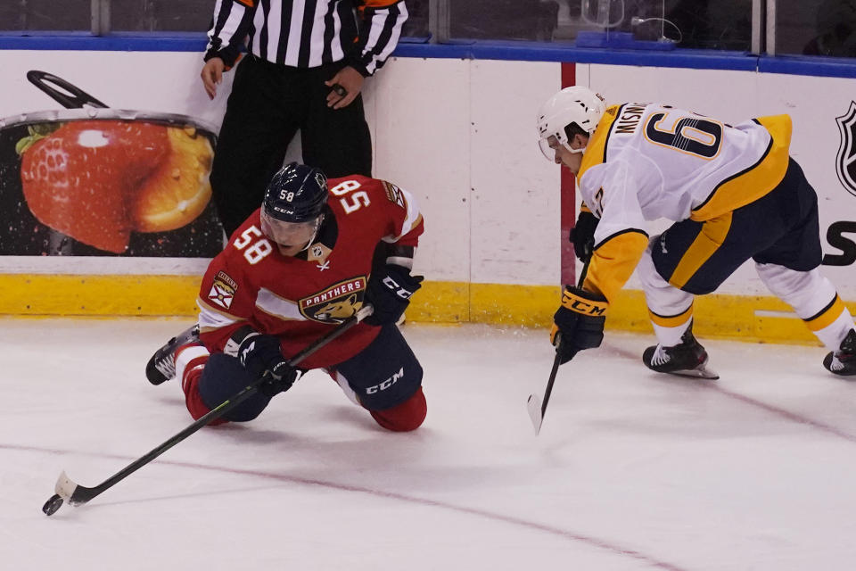 Florida Panthers defenseman Noah Juulsen (58) passes the puck as Nashville Predators center Grant Mismash (62) defends, during the first period at an NHL preseason second doubleheader hockey game, Sunday, Sept. 26, 2021, in Sunrise, Fla. (AP Photo/Marta Lavandier)