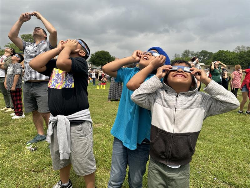 Third grade students from Reilly Elementary Josue Victorian, from left, Dennis Ixm Choj and Fidencio Caal look up at the solar eclipse during their eclipse viewing party Monday, April 8, 2024, at the elementary school in Austin. The school held a viewing party for the students.