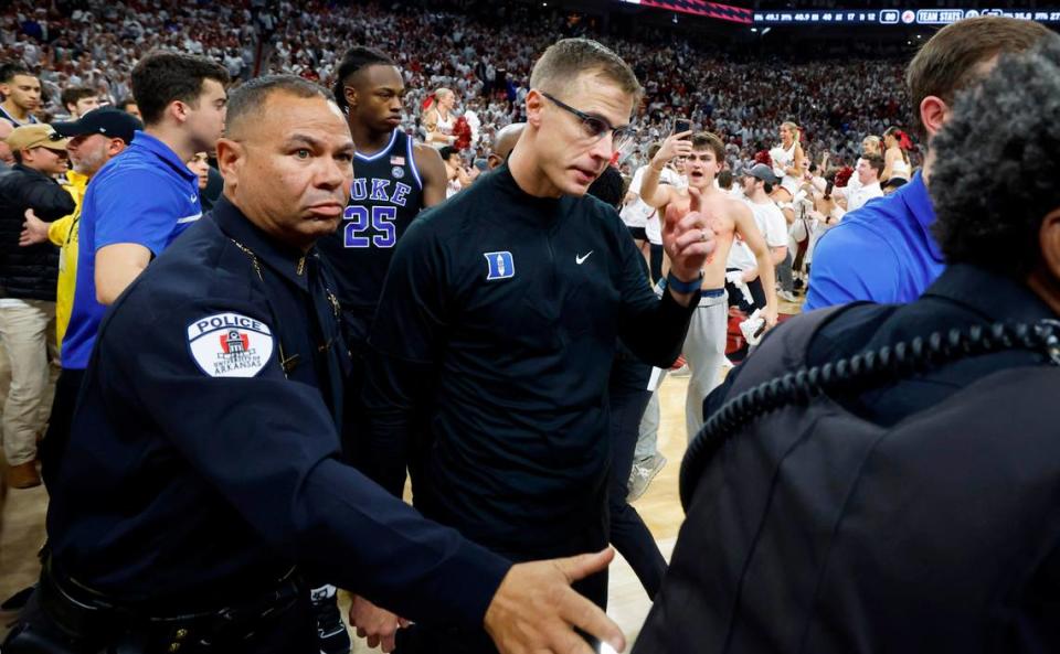 Duke’s head coach Jon Scheyer is escorted off as fans rush the court after Arkansas’ 80-75 victory over Duke at Bud Walton Arena in Fayetteville, Ark., Weds. Nov. 29, 2023.