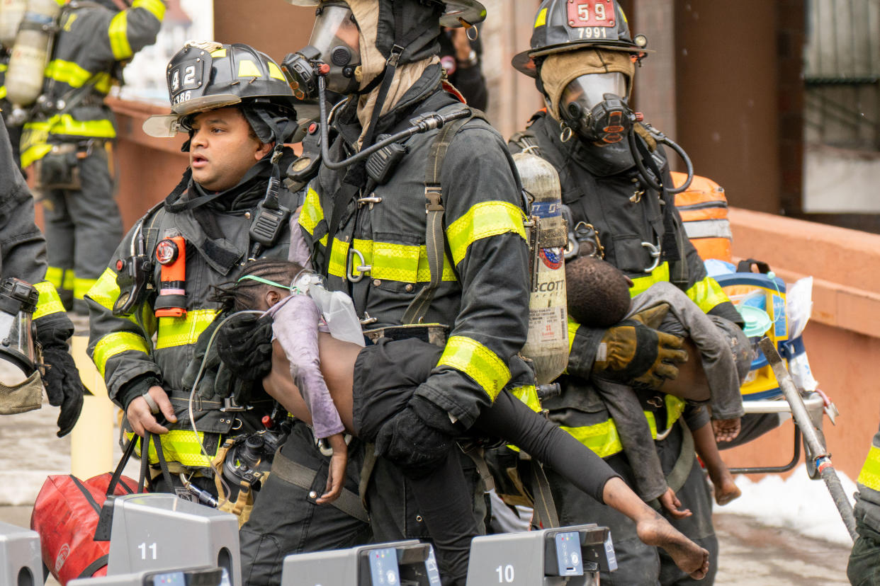 Firefighters carry children out of a building in the Bronx on Sunday.