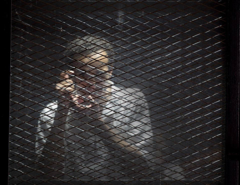 FILE - In this July 28, 2018 file photo, Egyptian photojournalist Mahmoud Abu Zied, known by his nickname Shawkan, gestures in a soundproof glass cage inside a makeshift courtroom in Tora prison in Cairo. Egypt has created a new high-powered human rights watchdog agency, but its primary mission isn’t to protect Egyptians from violations. Instead, the body is primarily aimed at protecting the government from allegations of rights abuses, especially those made by international groups. The new body reflects an attitude of the state under President Abdel-Fattah el-Sissi that sees accusations of human rights violations to be intended to undermine the government and cause instability. (AP Photo/Amr Nabil, File)