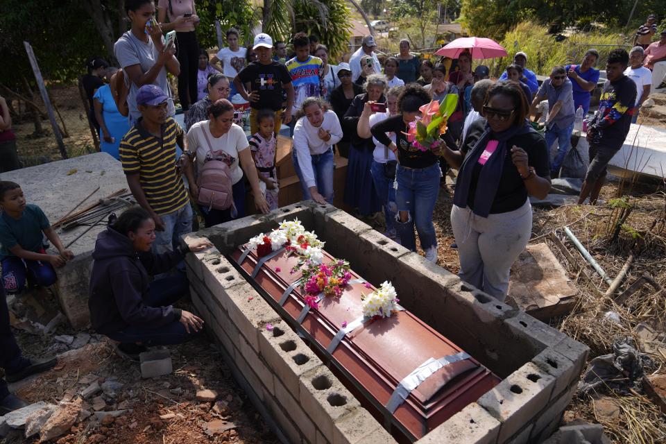 The sister of miner Santiago Mora, left, cries as he is buried at the cemetery in La Paragua, Bolivar state, Venezuela, Thursday, Feb. 22, 2024. The collapse of an illegally operated open-pit gold mine in central Venezuela killed at least 14 people and injured several more, state authorities said Wednesday, as some other officials reported an undetermined number of people could be trapped. (AP Photo/Ariana Cubillos)