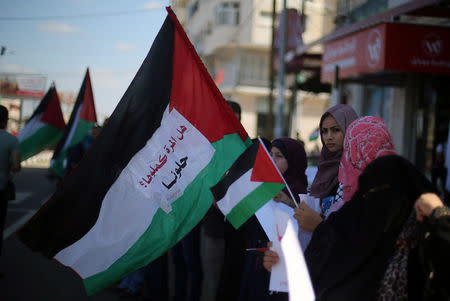 Women hold Palestinian flags as they celebrate after rival Palestinian factions Hamas and Fatah signed a reconciliation deal, in the central Gaza Strip October 12, 2017. REUTERS/Ibraheem Abu Mustafa